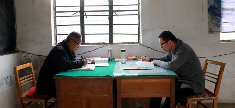        3月26日，董運青老師（左）和王峰老師（右）在簡陋的辦公室里備課、批改作業。