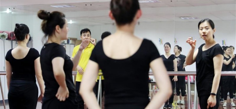 5月26日，兩名舞蹈隊員在聊天。 在上海閔行區古美路街道，有一個由聽力障礙者組成的舞蹈團隊——古美彩韻聾人舞蹈藝術隊。舞蹈隊現有20名隊員，年齡從20歲到40歲，由上海戲劇學院舞蹈學院的老師每周一次為隊員們提供訓練指導。對舞蹈藝術的熱愛，讓這些聽力障礙者走到了一起，在無聲世界里舞出精彩人生。