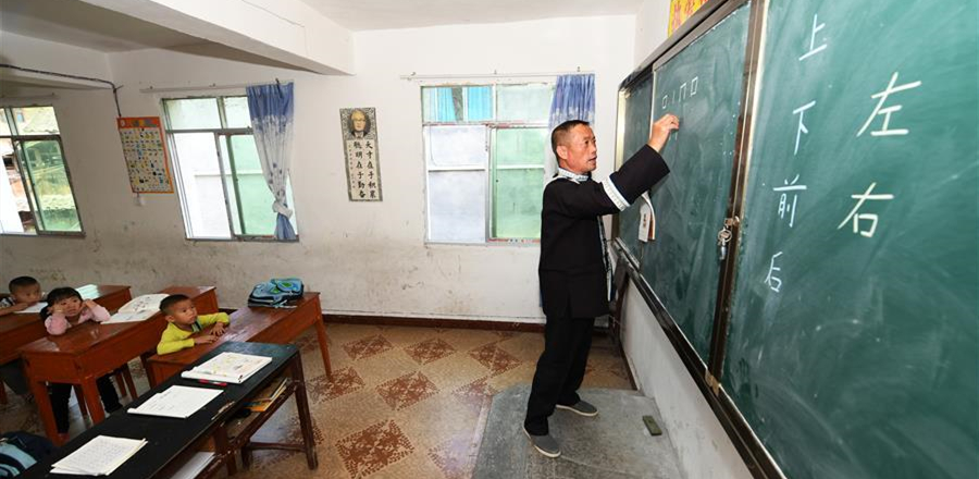 今年56歲的姜同英，是貴州省黔東南苗族侗族自治州劍河縣磻溪鎮化敖小學的一名侗族教師。1982年以來，姜同英從村里的代課教師做起，后由民辦轉為公辦教師。學校里也曾先后考來多位年輕老師，最終都因環境艱苦、交通不便而選擇離開。只有姜同英留了下來，在化敖小學一守就是37年。2013年后，隨著當地外出務工村民和易地扶貧搬遷戶的增多，化敖小學的生源變得越來越少。目前學校只剩下一二年級的11名學生和幼兒園的10名孩子，姜同英便采取“復式教學”的教學方式。“姜老師總像對待自己孩子一樣對待我們的孩子。”村民們這樣評價姜同英。37年來，姜同英一邊教授農村孩子文化知識，一邊悉心照料著學生們的生活起居，堅守在深山里的教學點。2014年，姜同英獲得“全國優秀教師”榮譽稱號，2016年入選“貴州好人榜”。“我喜歡這里的孩子，我愿意在這兒做一輩子老師。”姜同英說。圖為姜同英在給學生們上語文課。