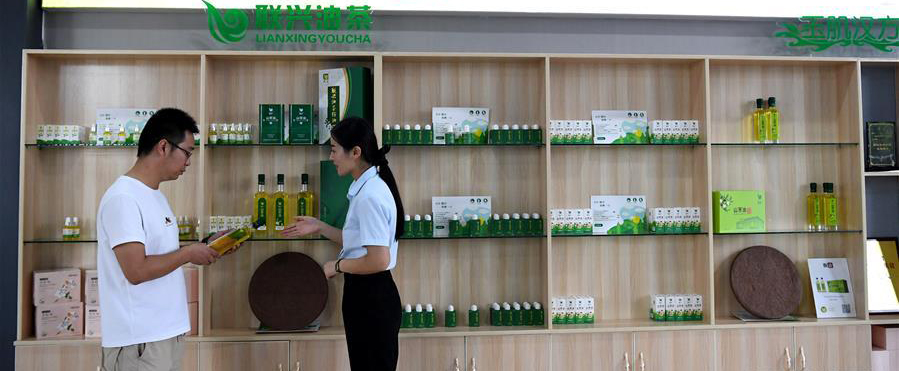 8月25日，在河南省光山縣一家油茶加工企業展廳內，工作人員（右）向顧客介紹產品。 