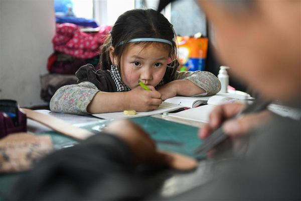        4月15日，在錫尼河鎮的出租房內，女兒南吉樂瑪寫作業時看爸爸制作皮制品。新華社記者 劉磊 攝